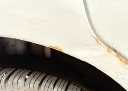 Spreading rust at edge: Rust forming around chipped paint on a car’s wheel arch.