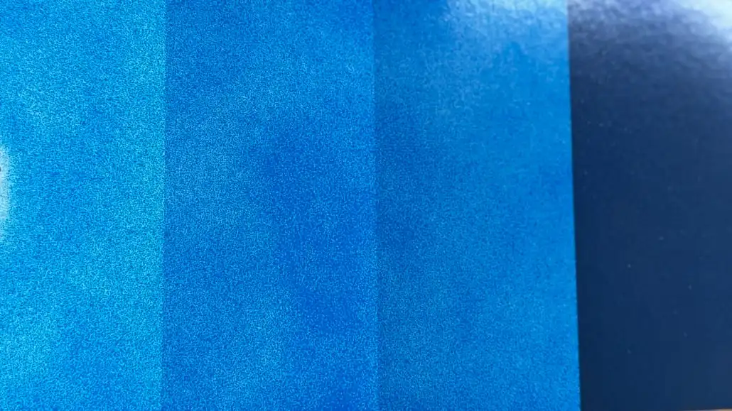 Single coat of blue automotive paint over a test card with white, grey, and black bands showing through, demonstrating blue pigment's low hiding power.