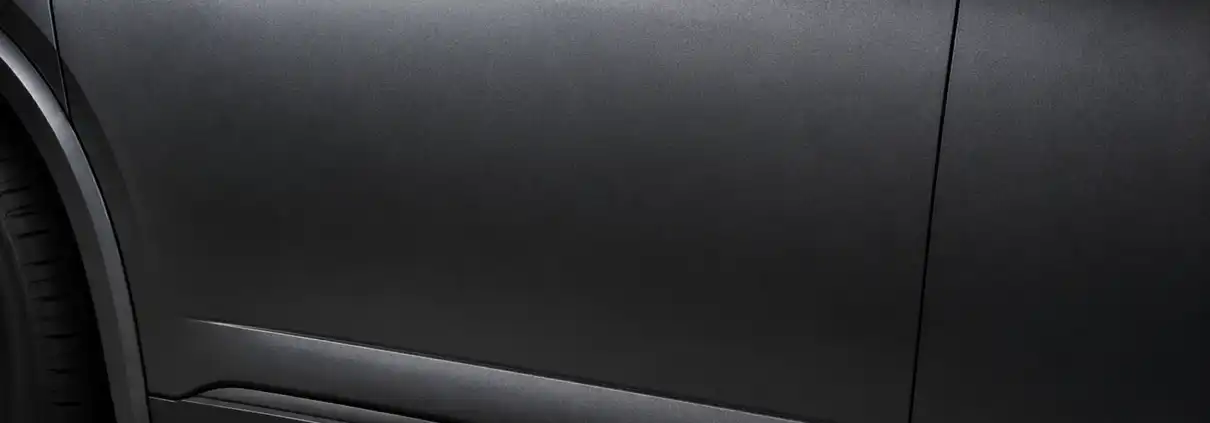 Close-up of a car door and lower body panel in deep matte gunmetal gray with a velvety non-reflective finish, echoing Acura's Gotham Gray Matte, illustrating the depth of premium multi-layer automotive paint.