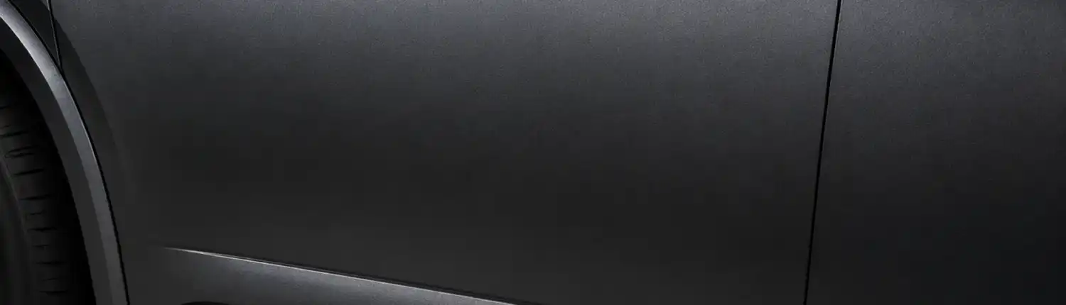 acura-gotham-gray-matte-body-panel-hero-1920-1080 Close-up of a car door and lower body panel in deep matte gunmetal gray with a velvety non-reflective finish, echoing Acura's Gotham Gray Matte, illustrating the depth of premium multi-layer automotive paint.